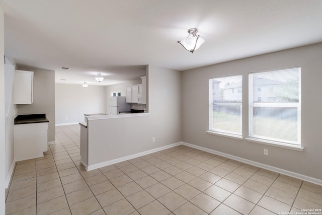 9618 Copper Fls, San Antonio, TX 78109 - kitchen with freestanding refrigerator, white cabinets, light tile patterned flooring, baseboards, and a peninsula