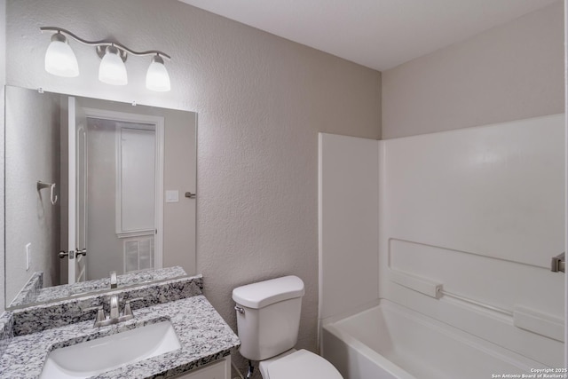 9618 Copper Fls, San Antonio, TX 78109 - bathroom featuring a textured wall, toilet, vanity, and shower / washtub combination