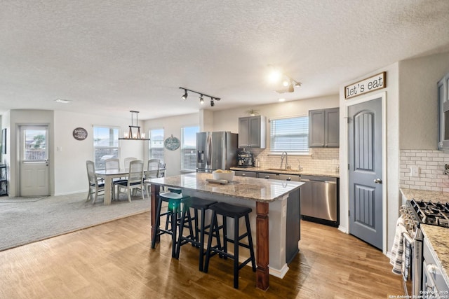 14721 Hooded Merganser, San Antonio, TX 78253 - kitchen featuring appliances with stainless steel finishes, a breakfast bar, a textured ceiling, light wood-style flooring, and tasteful backsplash