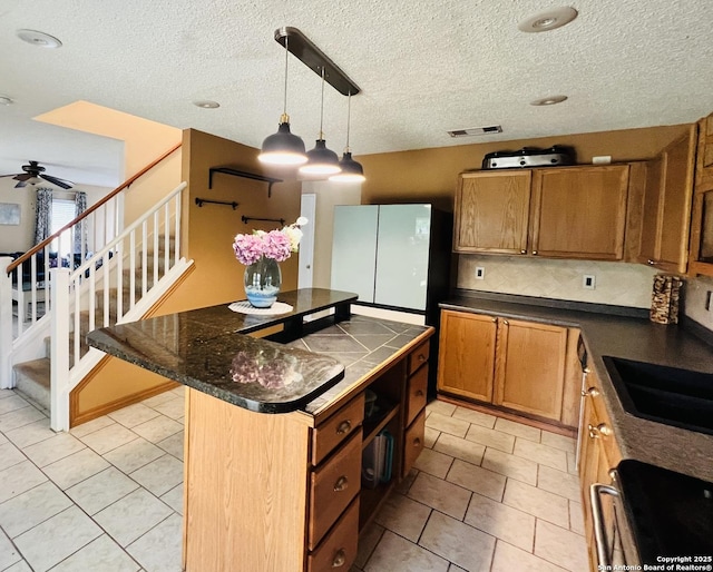 9208 Bowen, San Antonio, TX 78250 - kitchen featuring a center island, light tile patterned floors, freestanding refrigerator, a textured ceiling, and a sink
