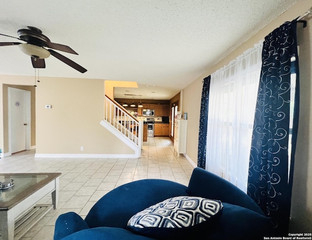 9208 Bowen, San Antonio, TX 78250 - living area featuring light tile patterned floors, ceiling fan, stairway, baseboards, and a textured ceiling