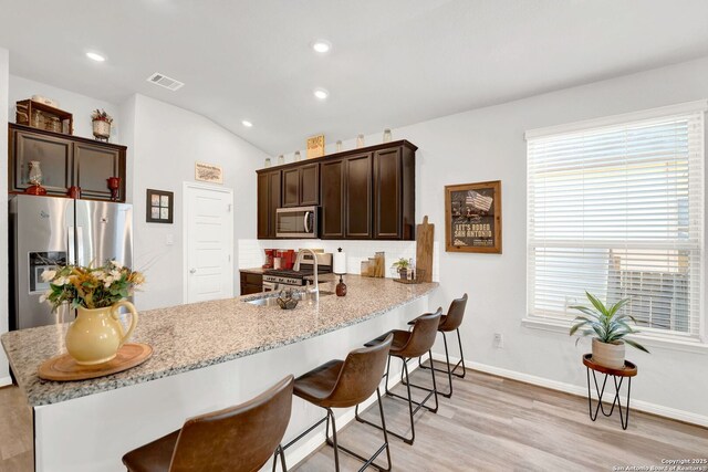 11706 Troubadour Trl, San Antonio, TX 78245 - kitchen with stainless steel appliances, light wood-style floors, a kitchen breakfast bar, a sink, and a peninsula