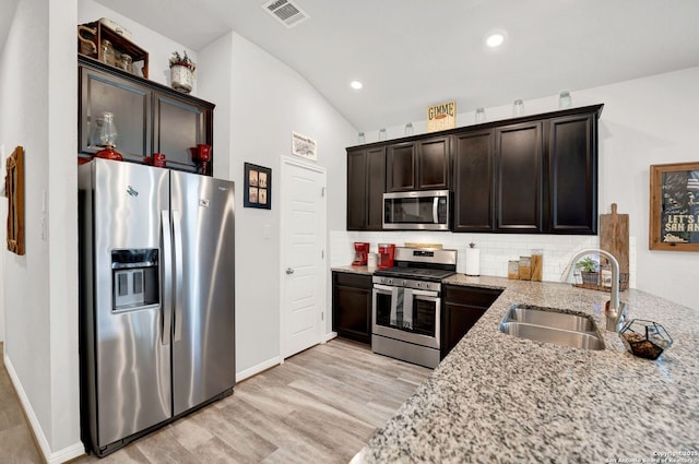 11706 Troubadour Trl, San Antonio, TX 78245 - kitchen with appliances with stainless steel finishes, a sink, light stone counters, backsplash, and light wood-type flooring
