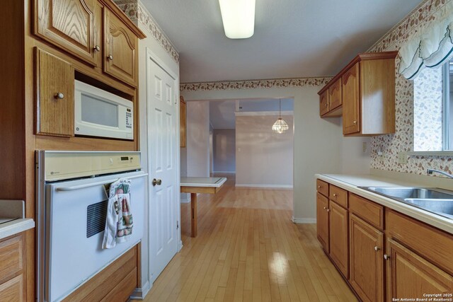 1306 Lytle, Kerrville, TX 78028 - kitchen featuring white appliances, brown cabinets, light countertops, and light wood-style floors