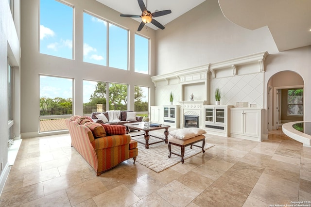 19223 Terra Rock, San Antonio, TX 78255 - living room with a high ceiling, a ceiling fan, arched walkways, plenty of natural light, and a fireplace