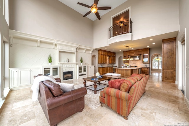 19223 Terra Rock, San Antonio, TX 78255 - living area with a high ceiling, a ceiling fan, arched walkways, baseboards, and a fireplace