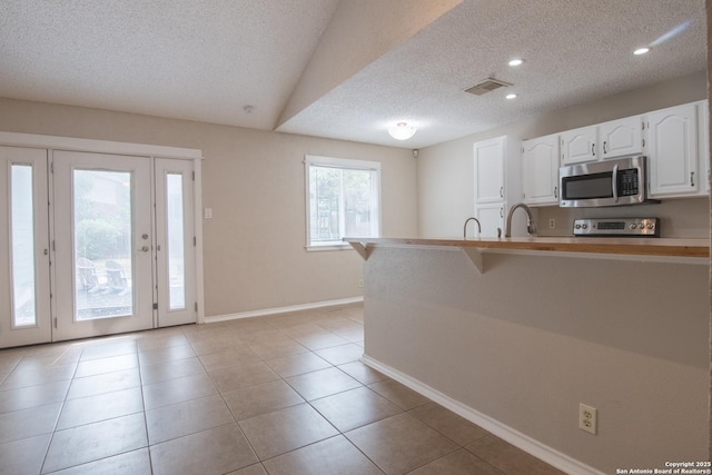7122 Ranch Hill Dr, San Antonio, TX 78250 - kitchen with stainless steel appliances, a textured ceiling, white cabinets, baseboards, and a sink