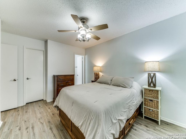16402 Blanco Ky, San Antonio, TX 78247 - bedroom with light wood-style flooring, a textured ceiling, baseboards, and a ceiling fan