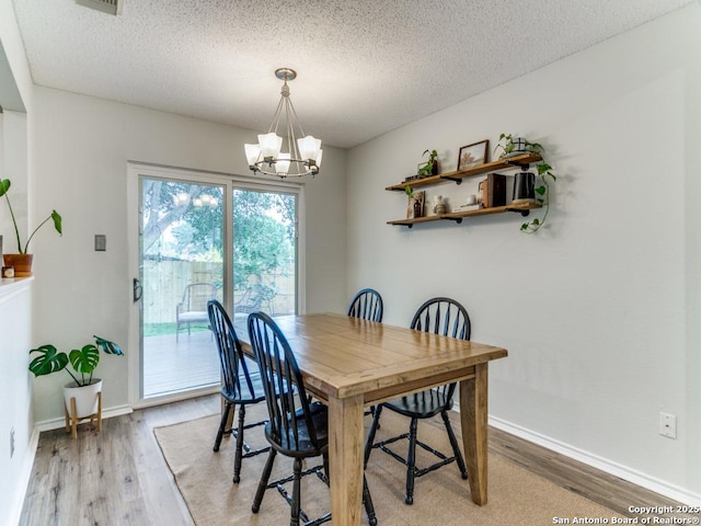 16402 Blanco Ky, San Antonio, TX 78247 - dining room with a chandelier, light wood-style flooring, a textured ceiling, and baseboards
