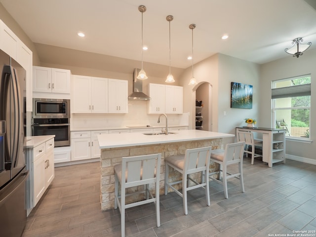 1006 Rock Shelter, San Antonio, TX 78260 - kitchen featuring appliances with stainless steel finishes, wall chimney exhaust hood, a sink, white cabinets, and a kitchen bar