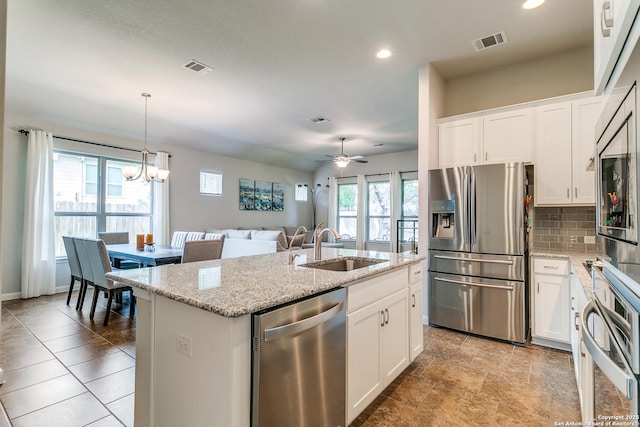 10250 Bricewood Pl, San Antonio, TX 78254 - kitchen featuring appliances with stainless steel finishes, a sink, decorative backsplash, an island with sink, and light stone countertops
