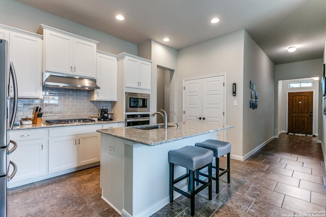 10250 Bricewood Pl, San Antonio, TX 78254 - kitchen with under cabinet range hood, a sink, appliances with stainless steel finishes, tasteful backsplash, and white cabinetry
