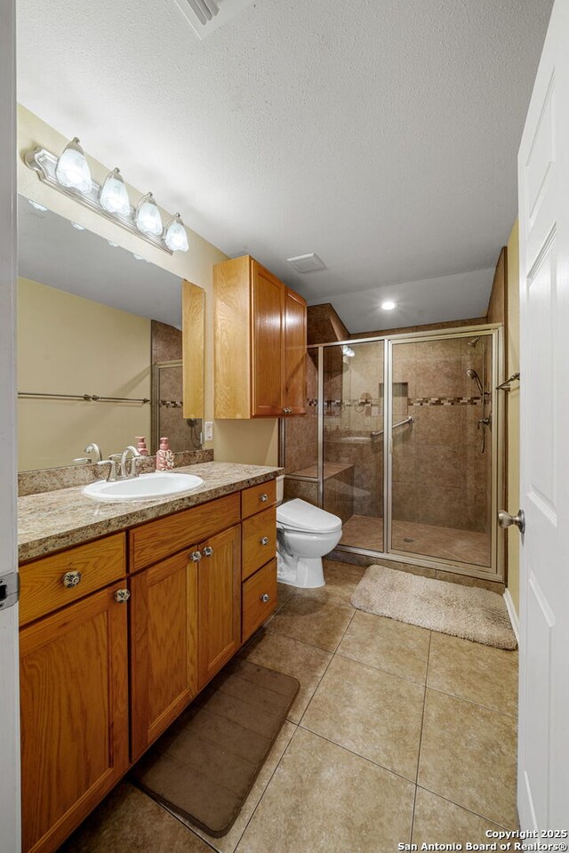 11301 Ford, Adkins, TX 78101 - bathroom featuring a shower stall, vanity, tile patterned floors, toilet, and a textured ceiling