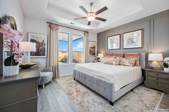 8644 Merlin Cv, San Antonio, TX 78222 - bedroom with a tray ceiling, wood finished floors, baseboards, and a ceiling fan