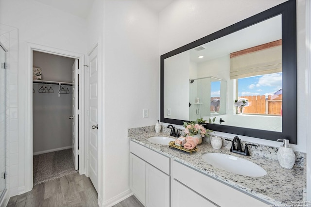 8644 Merlin Cv, San Antonio, TX 78222 - full bathroom featuring a shower stall, a spacious closet, double vanity, and wood finished floors