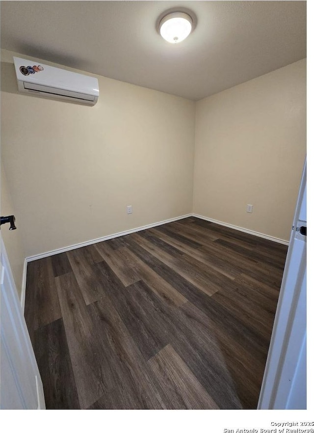 1924 Owens Ave, Groves, TX 77619 - empty room featuring a wall mounted air conditioner, dark wood finished floors, and baseboards