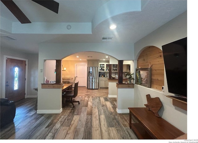 1924 Owens Ave, Groves, TX 77619 - kitchen featuring stainless steel fridge with ice dispenser, a peninsula, glass insert cabinets, arched walkways, and wood finished floors