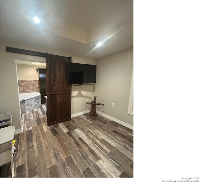 1924 Owens Ave, Groves, TX 77619 - unfurnished living room featuring a barn door, dark wood finished floors, and baseboards