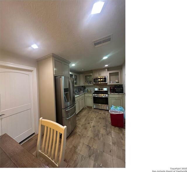 1924 Owens Ave, Groves, TX 77619 - kitchen with appliances with stainless steel finishes, wood finished floors, backsplash, glass insert cabinets, and recessed lighting