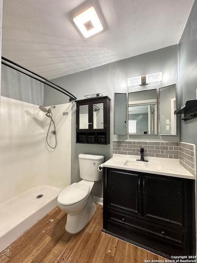 4835 Castle Sword, San Antonio, TX 78218 - full bath featuring wood finished floors, a stall shower, toilet, tasteful backsplash, and vanity