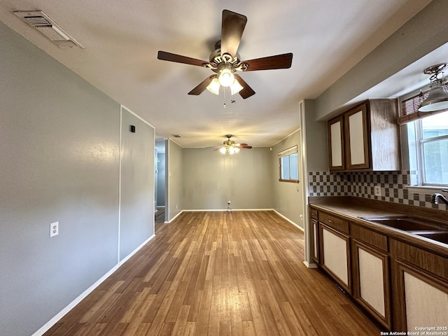 4835 Castle Sword, San Antonio, TX 78218 - kitchen featuring dark countertops, a sink, a ceiling fan, baseboards, and light wood-style flooring