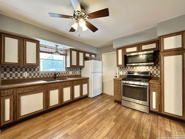 4835 Castle Sword, San Antonio, TX 78218 - kitchen with appliances with stainless steel finishes, a sink, tasteful backsplash, and light wood-style floors