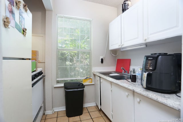 311 W Malone Ave, San Antonio, TX 78214 - kitchen with freestanding refrigerator, a sink, white cabinetry, and light tile patterned floors