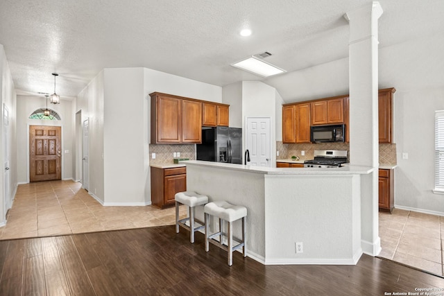 26430 Walden Oak, San Antonio, TX 78260 - kitchen featuring black appliances, brown cabinets, light countertops, light wood-style floors, and a textured ceiling