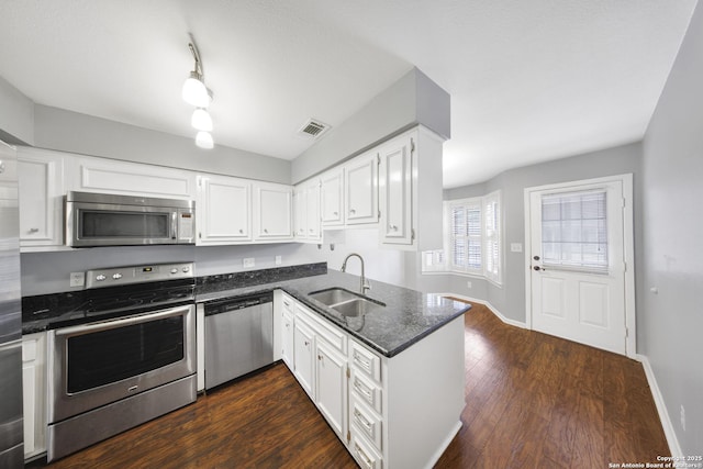 2611 Eisenhauer Unit 104A, San Antonio, TX 78209 - kitchen featuring stainless steel appliances, a sink, white cabinets, dark stone counters, and dark wood finished floors