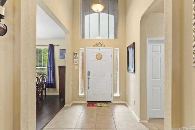 738 Daisy Xing, San Antonio, TX 78245 - foyer with arched walkways, light tile patterned floors, a high ceiling, and baseboards