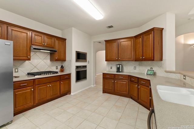26223 Cuyahoga Cir, San Antonio, TX 78260 - kitchen featuring arched walkways, stainless steel appliances, under cabinet range hood, and tasteful backsplash