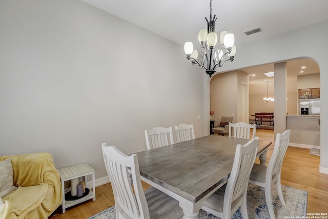 154 Roseheart, San Antonio, TX 78259 - dining area with a chandelier, arched walkways, light wood-style flooring, and baseboards