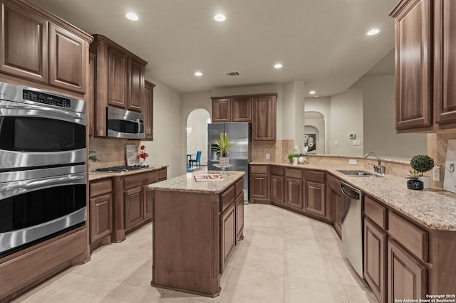 1238 Via Belcanto, San Antonio, TX 78260 - kitchen with arched walkways, appliances with stainless steel finishes, a sink, recessed lighting, and tasteful backsplash