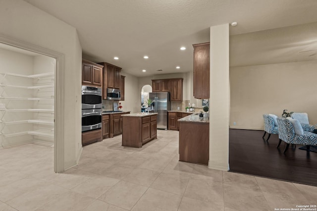 1238 Via Belcanto, San Antonio, TX 78260 - kitchen with stainless steel appliances, a center island, light stone counters, recessed lighting, and light tile patterned flooring