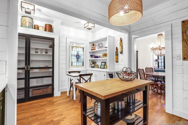 129 E Evergreen, Boerne, TX 78006 - dining room featuring a chandelier, light wood-type flooring, and wooden walls