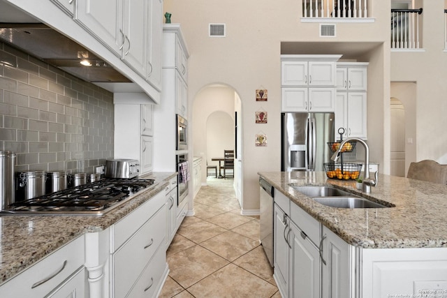 17906 Via Del Arbol, San Antonio, TX 78257 - kitchen with arched walkways, stainless steel appliances, a sink, white cabinets, and a towering ceiling