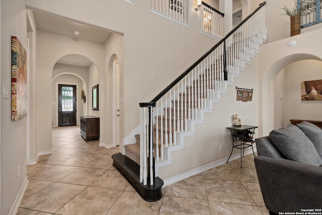 17906 Via Del Arbol, San Antonio, TX 78257 - foyer entrance with arched walkways, a towering ceiling, stairway, light tile patterned floors, and baseboards
