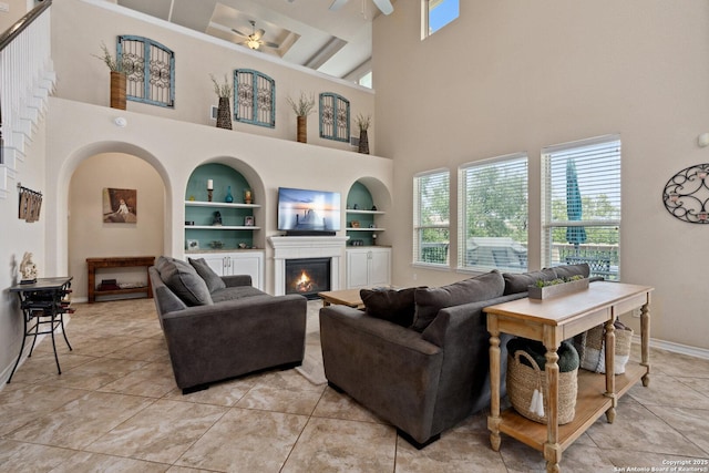 17906 Via Del Arbol, San Antonio, TX 78257 - living area featuring a warm lit fireplace, a towering ceiling, built in shelves, plenty of natural light, and ceiling fan