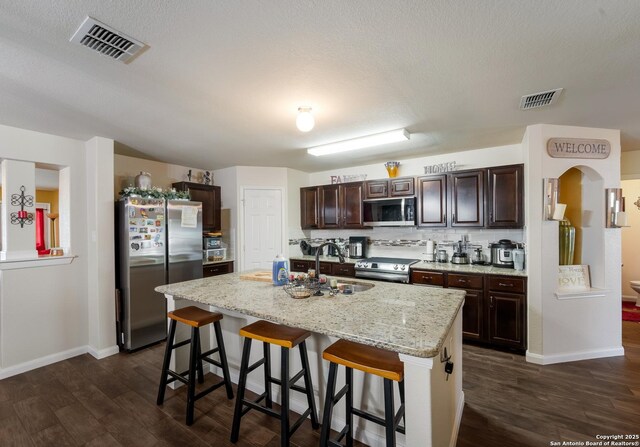 4310 Gambels Quail, Converse, TX 78109 - kitchen with appliances with stainless steel finishes, dark wood finished floors, a breakfast bar, dark brown cabinetry, and baseboards