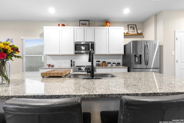 700 Ridge Vw, Seguin, TX 78155 - kitchen with stainless steel appliances, a breakfast bar, a sink, light stone countertops, and recessed lighting