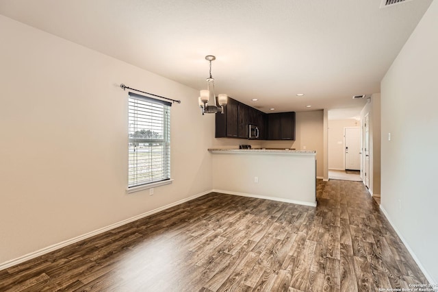 10110 Raspberry Oak, San Antonio, TX 78223 - kitchen with dark wood-style flooring, a chandelier, a peninsula, baseboards, and dark brown cabinets