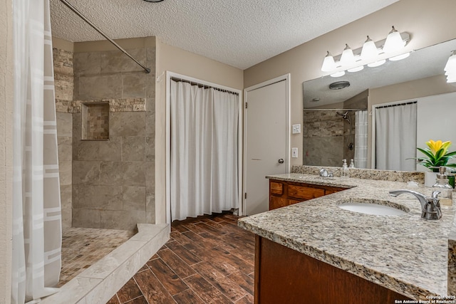 13426 Marceline, San Antonio, TX 78232 - full bathroom featuring a tile shower, a textured ceiling, wood finish floors, and double vanity