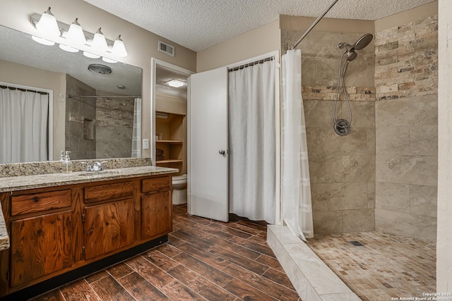 13426 Marceline, San Antonio, TX 78232 - bathroom with a textured ceiling, tiled shower, vanity, and toilet