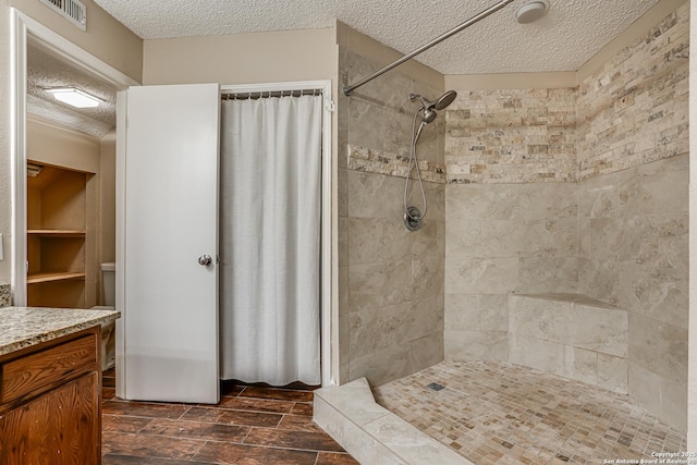 13426 Marceline, San Antonio, TX 78232 - bathroom featuring a textured ceiling, a tile shower, vanity, and wood finish floors