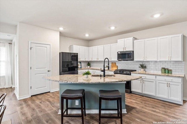 9702 Tupelo Holw, San Antonio, TX 78254 - kitchen featuring appliances with stainless steel finishes, a sink, backsplash, white cabinetry, and a kitchen bar
