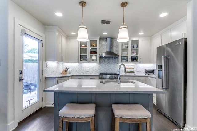 247 Brightwood Pl, San Antonio, TX 78209 - kitchen featuring stainless steel appliances, wall chimney exhaust hood, a sink, dark wood-style flooring, and light countertops