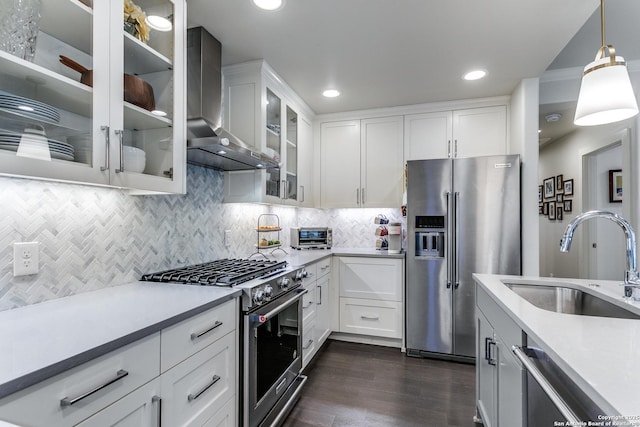 247 Brightwood Pl, San Antonio, TX 78209 - kitchen with stainless steel appliances, wall chimney exhaust hood, a sink, light countertops, and dark wood-type flooring