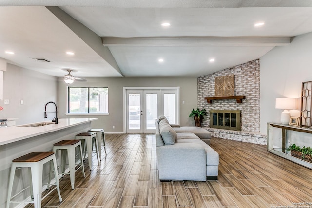 13603 Cobble Way, San Antonio, TX 78231 - living area featuring light wood-style floors, a ceiling fan, french doors, a brick fireplace, and baseboards