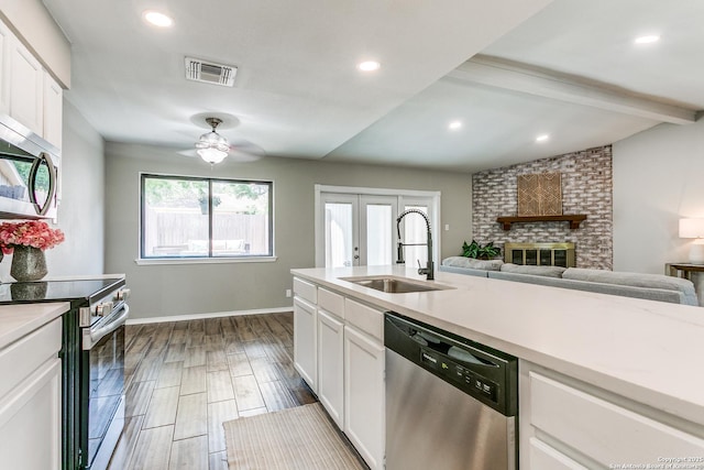 13603 Cobble Way, San Antonio, TX 78231 - kitchen with appliances with stainless steel finishes, a sink, ceiling fan, a brick fireplace, and light countertops