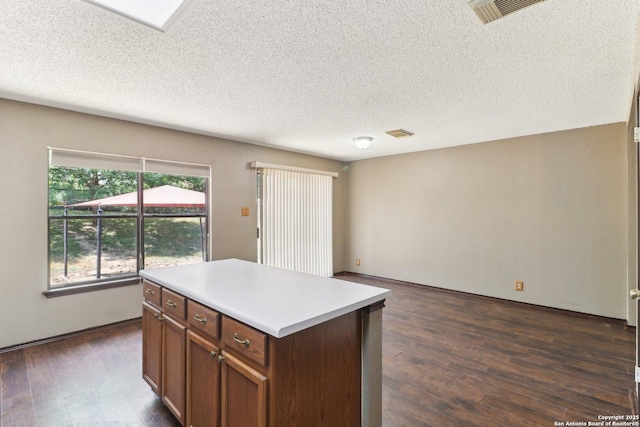 6831 Raintree Path, San Antonio, TX 78233 - kitchen featuring dark wood-style floors, light countertops, a textured ceiling, a kitchen island, and brown cabinetry